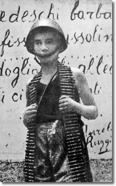 un ragazzino con un casco dell'esercito e con indosso una cartucciera 