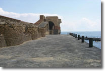pier of the castle with a low wall on the left surrounded by the sea