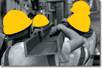 quattro operai trasportano una trave. i loro caschi protettivi sono evidenziati in giallo