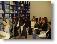 un gruppo di persone sedute in un'aula di una biblioteca
