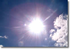 sole che si staglia su un cielo azzurro, attraversato da piccole nuvole